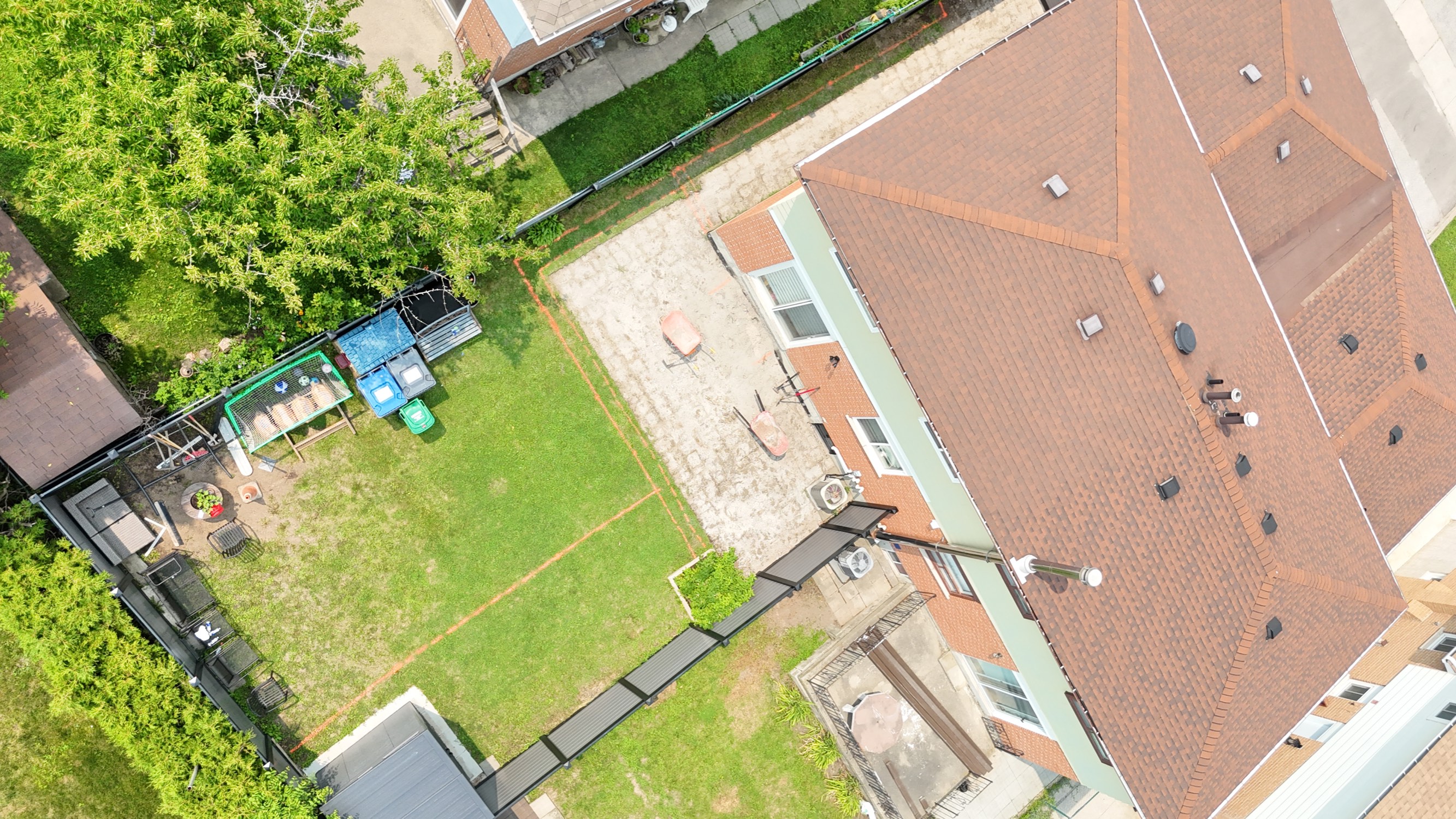 Aerial before photo of a Mississauga backyard with a patchy concrete slab patio, worn lawn and orange layout lines sprayed for the new patio
